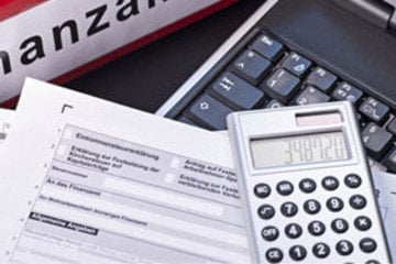 Ordner mit der Aufschrift Finanzamt, Steuerformulare, ein Taschenrechner und eine Laptoptastatur